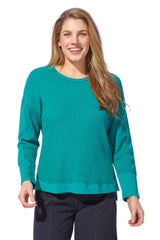 Woman wearing a teal sweater against a white background