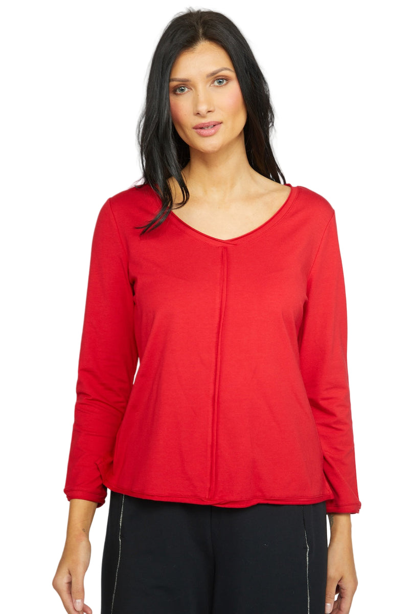 Woman wearing a red long-sleeve top against a gray background